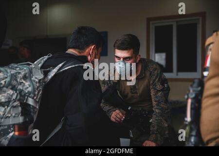 Une marine américaine affectée à la 24e unité expéditionnaire maritime (UMM) traite un évacué à l'aéroport international Hamid Karzaï, Kaboul, Afghanistan, le 15 août 2021. LES soldats AMÉRICAINS et les Marines aident le Département d'État américain à faire un retrait ordonné du personnel désigné en Afghanistan. Crédit obligatoire : Isaiah Campbell/US Marine corps via CNP Banque D'Images