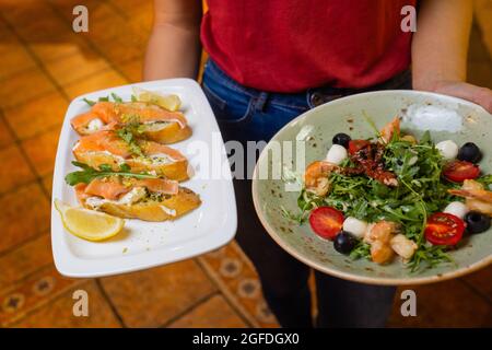 Femme serveur tenant un plateau en bois avec bruschetta dans elle main Banque D'Images