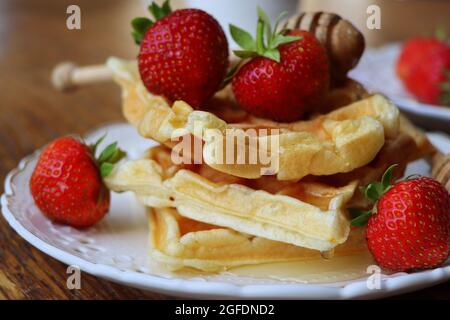 Gaufres belges avec baies fraîches, fraises, miel et cappuccino pour le petit déjeuner Banque D'Images