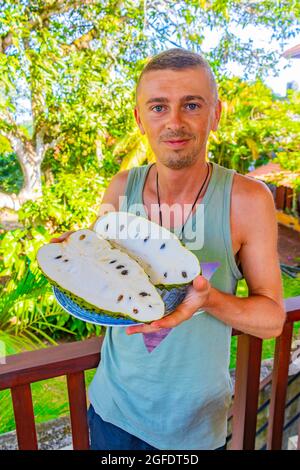 Touriste voyageur homme tient et présente en tranches de fruits sussop Sauersack Annona muricata tropical à Bentota Sri Lanka. Banque D'Images