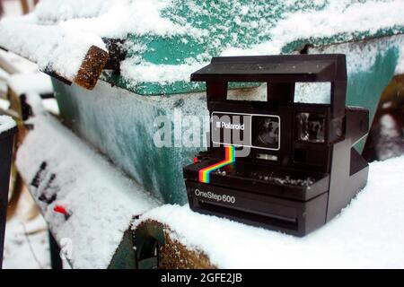 Un Polaroid One Step 600 se trouve près d'un contenant en métal sarcelle recouvert de neige Banque D'Images