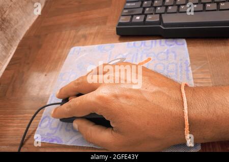 Image de la main femelle cliquant sur la souris d'ordinateur. Un clavier d'ordinateur est placé à proximité. Banque D'Images