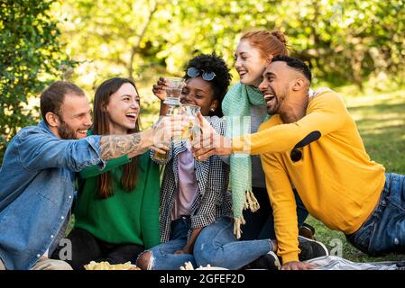De jeunes amis heureux qui toastent des boissons dans le jardin Banque D'Images