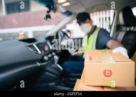 Un liveur prend une boîte dans la voiture d'un ami pour la livrer à un client, sélectionnez Focus a Box. Banque D'Images
