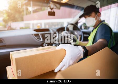 Un liveur qui tient le lecteur de carte de crédit prend une boîte dans la voiture d'un ami pour la livrer à un client, sélectionnez Focus une boîte. Banque D'Images