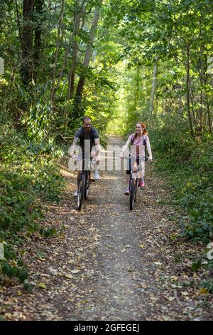 Jeune couple à vélo en forêt Banque D'Images