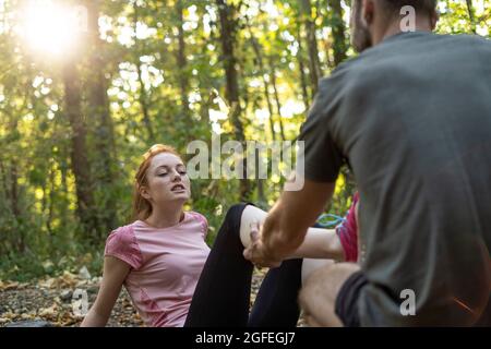 Jeune couple s'exerçant sur la piste de terre dans la forêt Banque D'Images