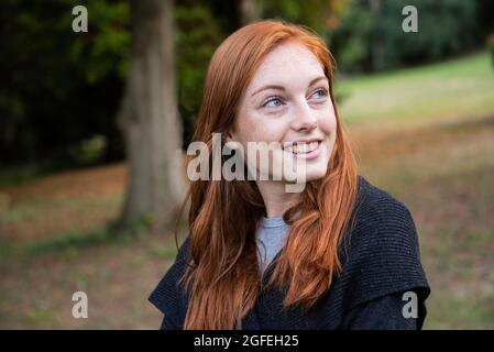 Jeune femme souriante assise dans un parc public Banque D'Images