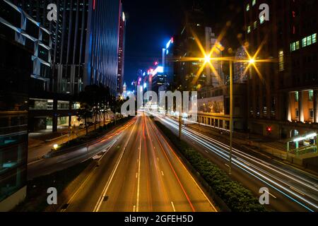 Vue extérieure du paysage urbain moderne avec une longue exposition des véhicules qui se déplacent dans la rue à Hong Kong Banque D'Images