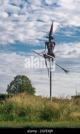 Zonnebeke, Belgique - 2 août 2021 : sorcière en métal noir sur la statue à balai au milieu du rond-point sur l'A19 et sur les routes N303 sous un paysage bleu. Vert Banque D'Images