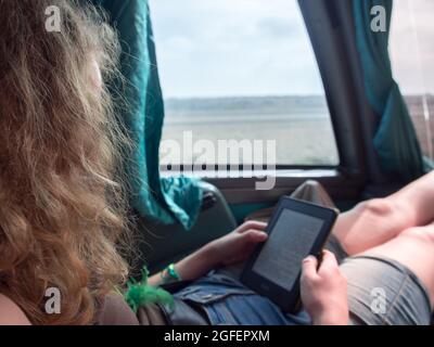 Une jeune femme lisant un livre électronique sur Kindle lorsqu'elle voyage dans le bus. Banque D'Images