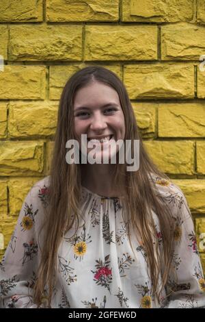 Portrait en gros plan d'une jolie jeune femme en robe décontractée souriant avec les dents. Cheveux longs et droits blonds. Beauté naturelle sans maquillage Banque D'Images