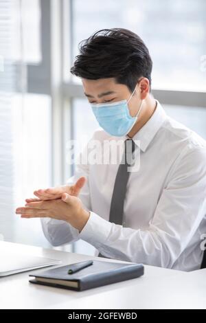 Jeune homme d'affaires utilisant l'assainisseur pour les mains dans le bureau Banque D'Images