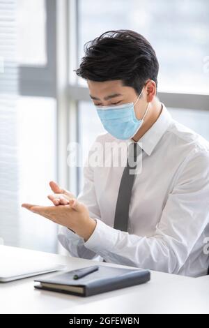 Jeune homme d'affaires utilisant l'assainisseur pour les mains dans le bureau Banque D'Images