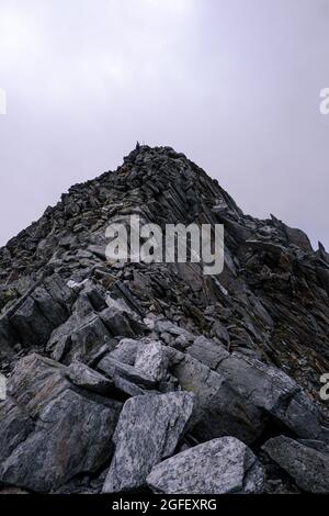 Grimpez au sommet d'une montagne rocheuse entourée de nuages Banque D'Images