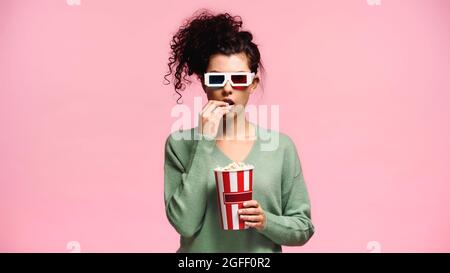 femme surprise en lunettes 3d mangeant du pop-corn isolé sur rose Banque D'Images