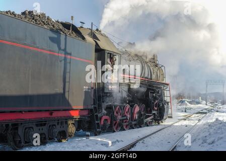 SORTAVALA, RUSSIE - 10 MARS 2021 : le conducteur de la locomotive regarde le stand de l'ancienne locomotive à vapeur soviétique lors d'une journée d'hiver Banque D'Images