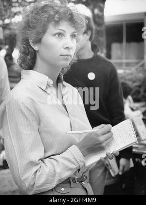 Austin Texas USA, vers 1984: Une étudiante de sexe féminin prend des notes dans le bloc-notes de sa journaliste tout en couvrant un événement en plein air. ©Bob Daemmrich Banque D'Images