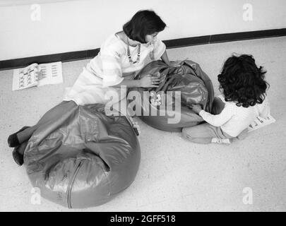 Austin Texas Etats-Unis, 1988: Éducation spéciale féminine hispanique: Salon d'enseignant et d'étudiant sur des chaises de beanbag dans une salle de classe informelle, MR RR-0177 ©Bob Daemmrich Banque D'Images