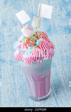 Milkshake bleu et rose décoré de guimauves sur fond bleu. Banque D'Images