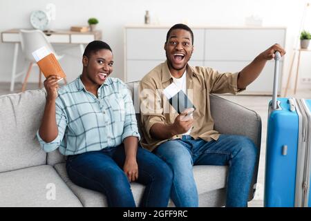 Joyeux couple de touristes africains tenant des billets de voyage à la maison Banque D'Images