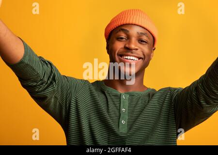 Autoportrait. Joyeux homme américain africain prenant Selfie sur fond jaune Banque D'Images