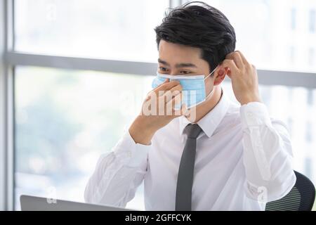 Jeune homme d'affaires portant un masque chirurgical au bureau Banque D'Images