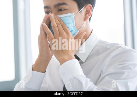 Jeune homme d'affaires portant un masque chirurgical au bureau Banque D'Images