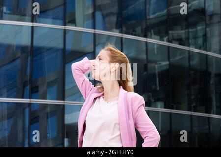 Jeune belle femme blonde avec de longs cheveux dans des vêtements roses élégants Banque D'Images