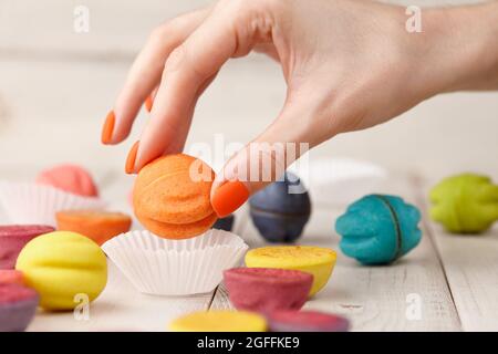 La main de femme prend le cookie de couleur de la table Banque D'Images