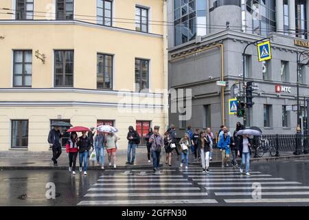 Saint-Pétersbourg, Russie - 9 août 2021, les gens traversent la route dans une rue animée par temps de pluie Banque D'Images