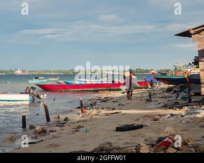 Kaimana, Arguni Bay, Indonésie - février 2018 : problème de pollution. Bateaux en bois et plein de déchets sur la plage à marée basse au port d'un petit Banque D'Images