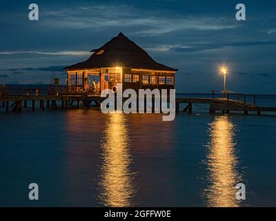 Ora Beach, Indonésie - 14 février 2018 : maisons sur l'eau dans le complexe Ora Beach, nuit. SERAM Island, Centre de Maluku, Indonésie Banque D'Images