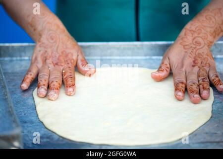 Femme avec tatouages au henné sur les mains préparant des crêpes.Msemin pâte à pain plat ronde préparée sur le gril, Marrakech, Maroc Essaouira, Maroc Banque D'Images