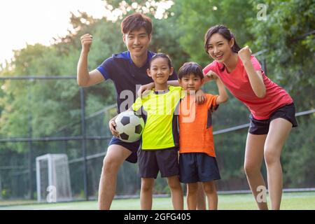 Bonne famille jouant au football sur le terrain Banque D'Images