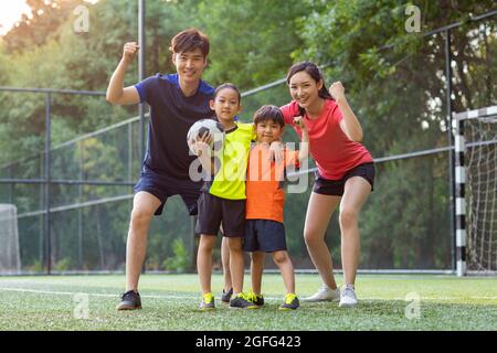 Bonne famille jouant au football sur le terrain Banque D'Images