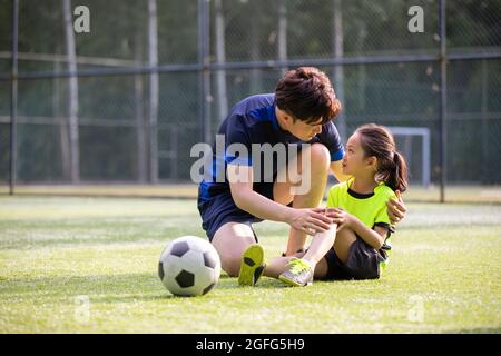 Père prenant soin de sa fille blessée sur le terrain de football Banque D'Images