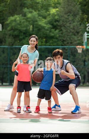 Bonne famille jouant au basket-ball sur l'aire de jeux Banque D'Images