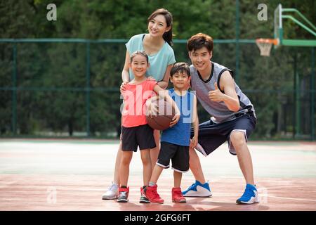 Bonne famille jouant au basket-ball sur l'aire de jeux Banque D'Images