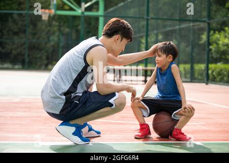 Père et fils heureux jouant au basket-ball sur l'aire de jeux Banque D'Images