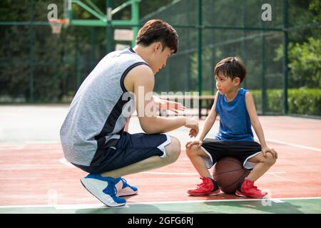 Père et fils heureux jouant au basket-ball sur l'aire de jeux Banque D'Images