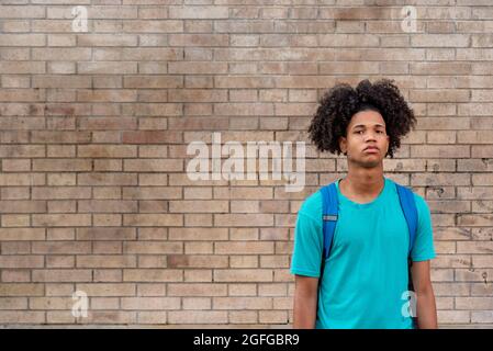 Afro latin homme adolescent contre un mur, regardant vers le haut. Banque D'Images