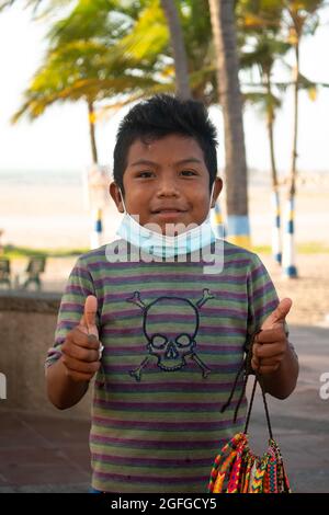 Riohacha, la Guajira, Colombie - Mai 26 2021: Portrait d'un Wayuu Boy vêtu d'un T-shirt rayé, portant un masque sous sa bouche et regardant le C Banque D'Images