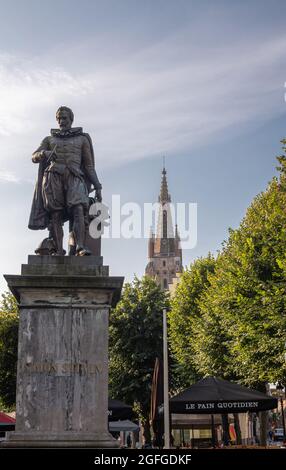 Brugge, Flandre, Belgique - 4 août 2021 : gros plan de la statue de bronze de Simon Stevin sur un piédestal gris avec la flèche de la cathédrale notre-Dame au dos sous le bleu Banque D'Images