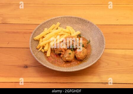 Boulettes de poulet compotées de légumes garnis de frites sur une assiette grise Banque D'Images