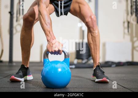 Gros plan d'un homme musclé soulevant une grosse kettlebell. Photo de haute qualité. Banque D'Images