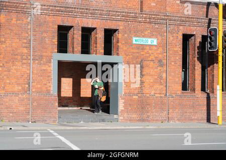 Wellington Nouvelle-Zélande - juillet 31 2021; femme en vert bouclier les yeux du soleil comme elle entre dans la galerie ouvrant dans la rue du patrimoine de laine hangar connu a Banque D'Images