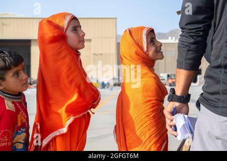 Les passagers attendent de monter à bord d'un Globemaster III de la US Air Force C-17 affecté au 816e escadron de transport aérien expéditionnaire en appui à l'évacuation en Afghanistan à l'aéroport international Hamid Karzaï (HKIA), en Afghanistan, le 24 août 2021. (É.-U. Photo de la Force aérienne par le Sgt. Donald R. Allen) Banque D'Images