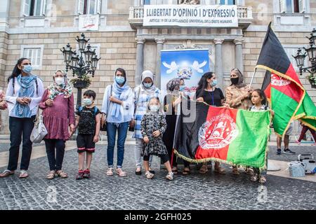 Barcelone, Espagne. 25 août 2021. Les manifestants détiennent les drapeaux de l'Afghanistan lors de la manifestation devant la Generalitat de Catalogne. L'association afghane de Barcelone a manifesté devant la Generalitat de Catalogne pour demander au gouvernement la protection et l'évacuation de leurs familles qui sont restées en Afghanistan. Crédit : SOPA Images Limited/Alamy Live News Banque D'Images