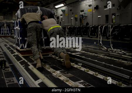 Des membres du 8e Escadron de mobilité aérienne expéditionnaire chargent du fret sur un C-17 Globemaster III pour une mission de livraison aérienne en Afghanistan. L'équipage de conduite C-17 a livré la cargaison qui consistait en du carburant et d'autres fournitures diverses à une base d'exploitation éloignée en Afghanistan. Banque D'Images